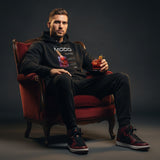 Man sitting in a red chair holding a glass of negroni, wearing a black hoodie with with QR code for AR video activation.