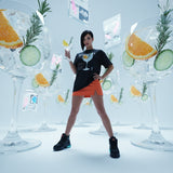 Female model in a stylish outfit wearing a black t-shirt with with QR code for AR video activation, standing in front of large glass drinks with garnishes.