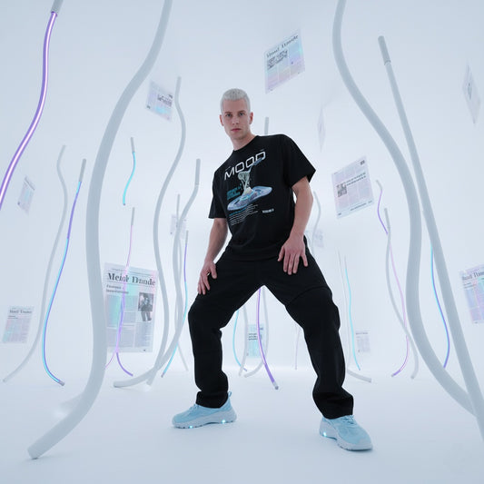 male model wearing a black t-shirt with QR code for AR video activation, in a futuristic setting with curved white walls and blue lights.