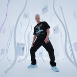 male model wearing a black t-shirt with QR code for AR video activation, in a futuristic setting with curved white walls and blue lights.