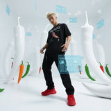 male model wearing a black t-shirt with QR code for AR video activation, red shoes in a futuristic setting with digital elements and giant chili peppers.